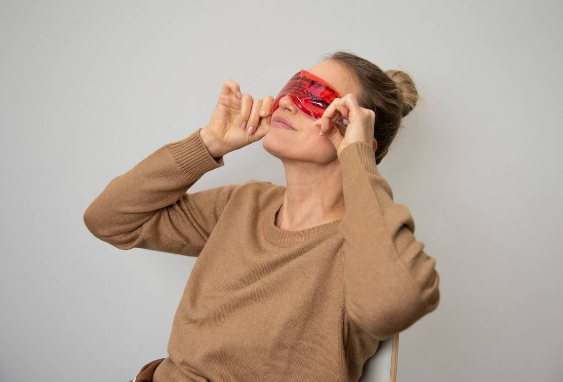 Frau setzt sich Augenmaske auf die Augen zur Entspannung