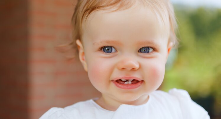 Lächelndes Kleinkind mit ersten Zähnen | © Adobe Stock