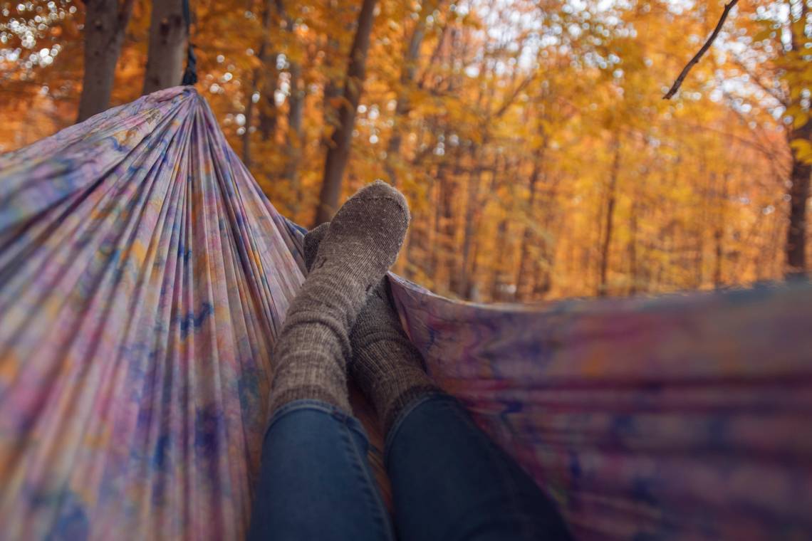Hängematte im Herbstwald. Man sieht Beine und Füsse in Wollsocken in der Hängematte. | © Nicole Geri_via Unsplash