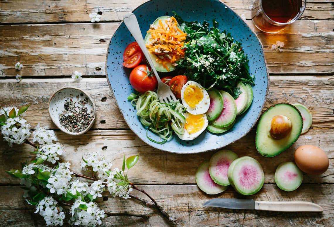 Holztisch mit dem Salatteller drauf mit Spinat, Avocado, Tomate und hartgekochten Eiern. | © Brooke Lark_via Unsplash